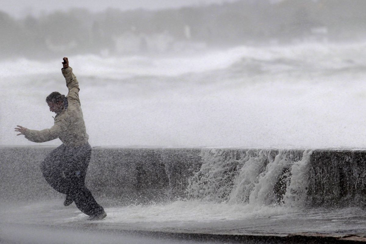 A man reacts to waves crashing over a seawall in Narragansett, R.I., Monday, Oct. 29, 2012.  A fast-strengthening Hurricane Sandy churned north Monday, raking ghost-town cities along the Northeast corridor with rain and wind gusts. (Steven Senne / Associated Press)