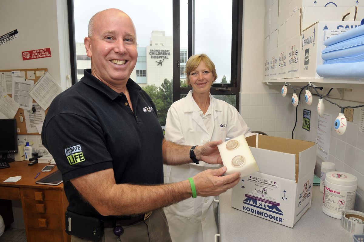 At the SightLife office in the Providence Sacred Heart Medical Center complex, Mike Meyer, left, holds the containers used to store and transport donated human corneas that Kelly Uttke, eye bank technician, right, recovers from donors around the region. (Jesse Tinsley)