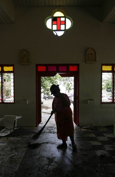 Leu Vaina, a resident of Asili village,  in American Samoa, helps clean  the Asili Catholic church on Thursday after an 8.0 quake Tuesday  triggered a tsunami.  (Associated Press / The Spokesman-Review)