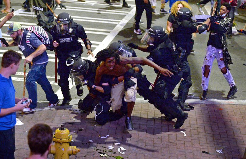 A protester, center, is taken into custody by Charlotte-Mecklenburg police officers in Charlotte, N.C., Wednesday, Sept. 21, 2016. Authorities in Charlotte tried to quell public anger Wednesday after a police officer shot a black man, but a dusk prayer vigil turned into a second night of violence, with police firing tear gas at angry protesters and a man being critically wounded by gunfire. North Carolina's governor declared a state of emergency in the city. (Jeff Siner/The Charlotte Observer via AP)