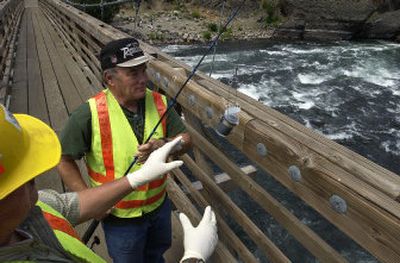 
City laboratory technician Gary Bussiere reels a Spokane River water sample into the hands of Scott Austin in Riverside State Park on Wednesday, a day after raw sewage was discovered spewing into the river from a city pipe. 
 (photos by DAN PELLE / The Spokesman-Review)