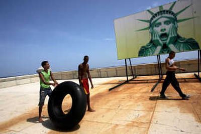 
Men walk past a billboard showing a cartoon of the Statue of Liberty at the Malecon in Havana on Thursday. During a ceremony marking the anniversary of the Cuban Revolution, acting President Raul Castro said Cuba has avoided the collapse the U.S. predicted before his brother Fidel fell ill. 
 (Associated Press / The Spokesman-Review)
