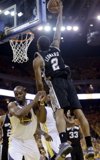 Spurs’ Kawhi Leonard dunks over forward Carl Landry. (Associated Press)