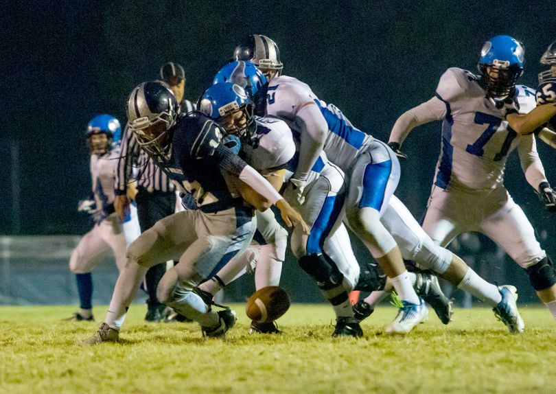 Coeur d’Alene’s Austin Chadderdon and Chase Blakley (21) force a fumble from Lake City quarterback Tucker Louie-McGee. (BRUCE TWITCHELL)