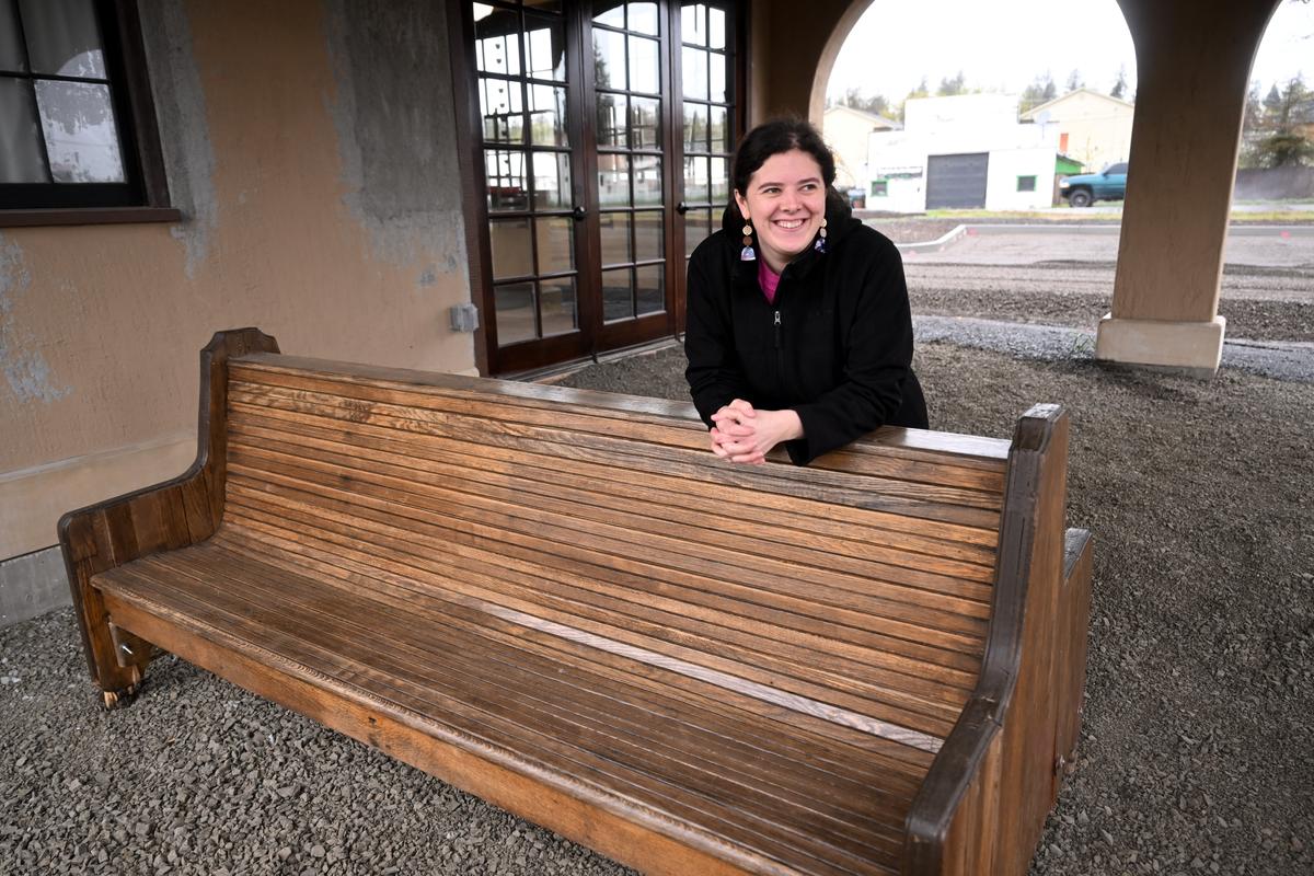 Cole Clark, a board member of the Cheney Depot Society, smiles on Wednesday as she shows a 100-year-old lobby bench that will soon be restored and returned to the Cheney Depot at 15 Union St. in Cheney.  (Tyler Tjomsland/The Spokesman-Review)