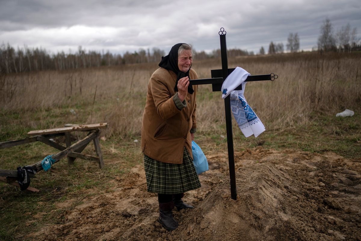 Nadiya Trubchaninova, 70, cries while holding the cross of her son Vadym, 48, who was killed by Russian soldiers last March 30 in Bucha, during his funeral on Saturday in the cemetery of Mykulychi, on the outskirts of Kyiv, Ukraine.  (Rodrigo Abd)