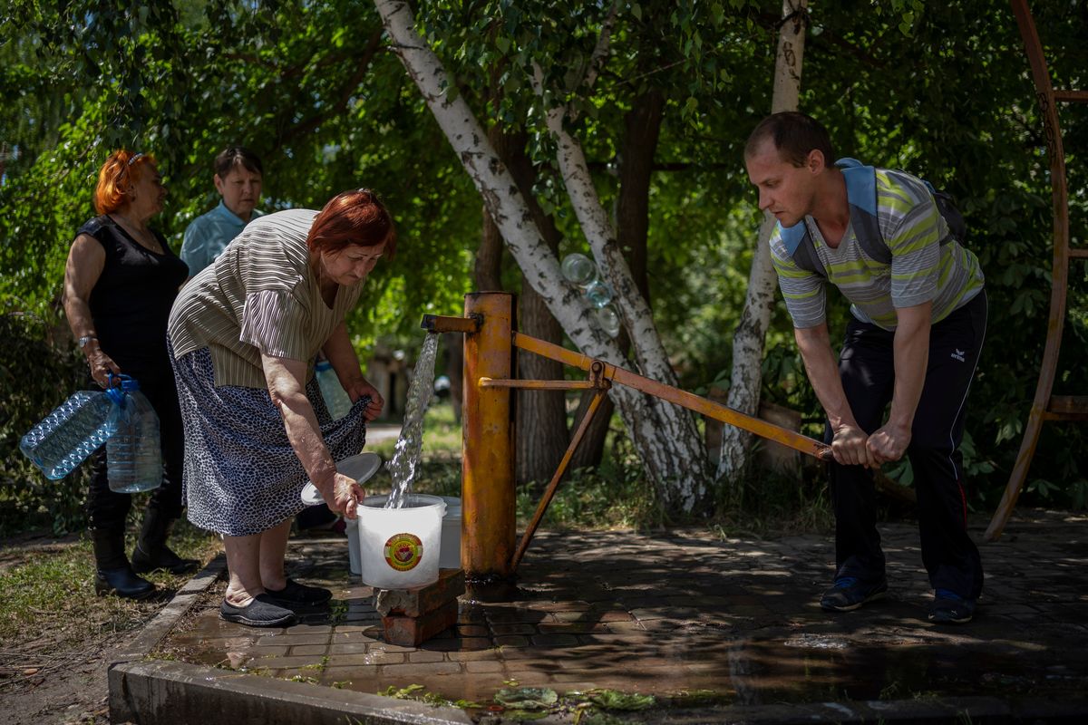 Residents gather to collect water from a pump in the street in Sloviansk, Ukraine, on Thursday.  (Elena Becatoros)