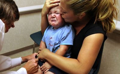 Aiden Rodriguez, 2, of Hayden, is comforted by his mother, Alysha Rodriguez, while getting his immunization shots at Panhandle Health in Hayden on Thursday. Administering the shot is registered nurse Mareva Kammeyer. (Kathy Plonka / The Spokesman-Review)
