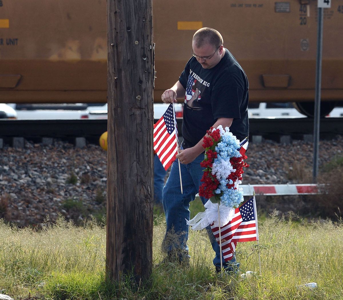 Midland, Texas resident Jerry Cook places a wreath his mother made and two U.S. flags Friday, Nov. 16, 2012 at the location where a train struck a flatbed trailer carrying veterans in a parade Thursday afternoon, killing four. (Mark Sterkel / Odessa American)
