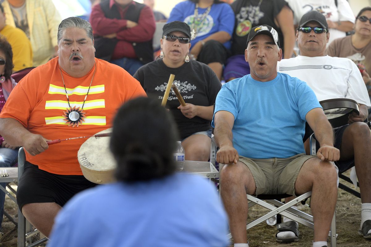 Teammates sing and drum while the opposite team tries to guess the location of a set of polished bones being concealed in the hands of the “hider” Monday at the Spokane Tribe’s powwow grounds in Wellpinit. (Jesse Tinsley)