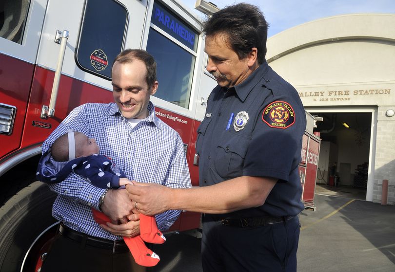 Joel Elgee, left, and paramedic Nick Muzik look at baby Leona, who was delivered Muzik’s help in Liberty Lake Jan. 25. (Jesse Tinsley)