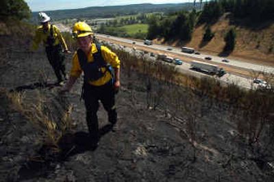 
Washington Department of Natural Resources firefighters Amber Bowers, right, and Chuck Tinney climb the burned-out hillside overlooking Interstate 5 and the Nisqually River on Friday in Lacey, Wash. Friday morning's fire apparently started along the freeway, then climbed the hill into a treeline surrounding several homes. 
 (Associated Press / The Spokesman-Review)
