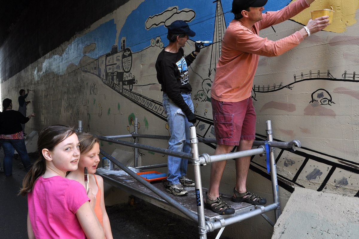 Intramural aesthetics: Joel Armstrong, right, and Jim Bingham paint the high spots Saturday on a mural outlined by Eastern Washington University art students in the tunnel on the Fish Lake Rail Trail near Marshall. Avery Steer, below left, and Morgan Armstrong worked at the lower levels on the feature along the popular paved bike route. (Rich Landers)