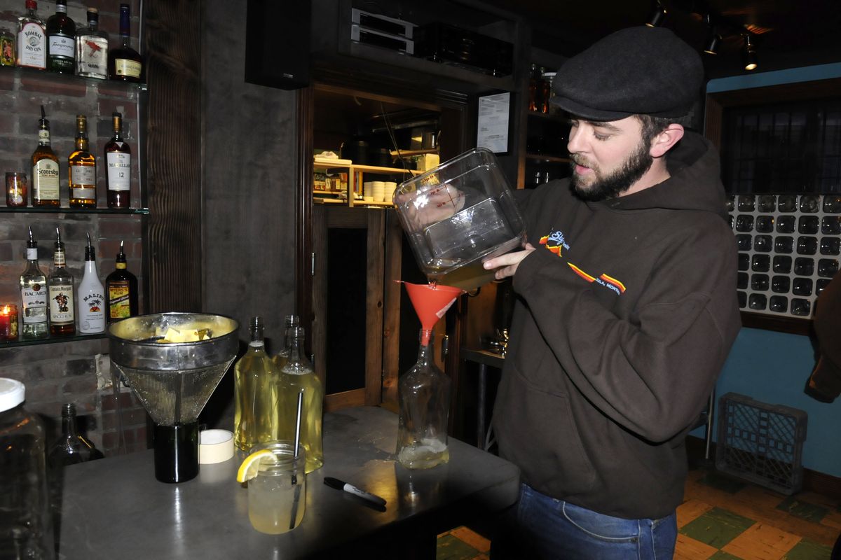 Marshall Powell, general manager of the Elk Public House family of restaurants in Spokane, pours tequila into bottles after removing the various concoctions he was using to infuse the liquor with special flavors at El Que, the group’s newest bar and restaurant. (Jesse Tinsley)