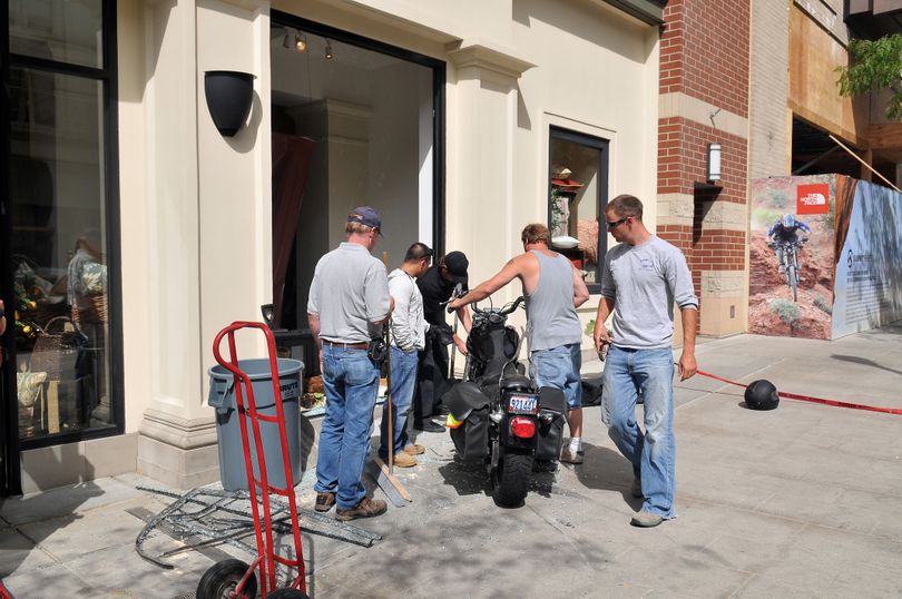 River Park Square personnel and others help move a Harley-Davidson motorcycle out of the window at the Pottery Barn store on Main Avenue on Thursday.  The rider, leaving Red Robin across the street, shot across Main and into the window, possibly with a stuck throttle. The driver was taken away to be treated for several cuts to his face, arms and legs. (Jesse Tinsley / The Spokesman-Review)