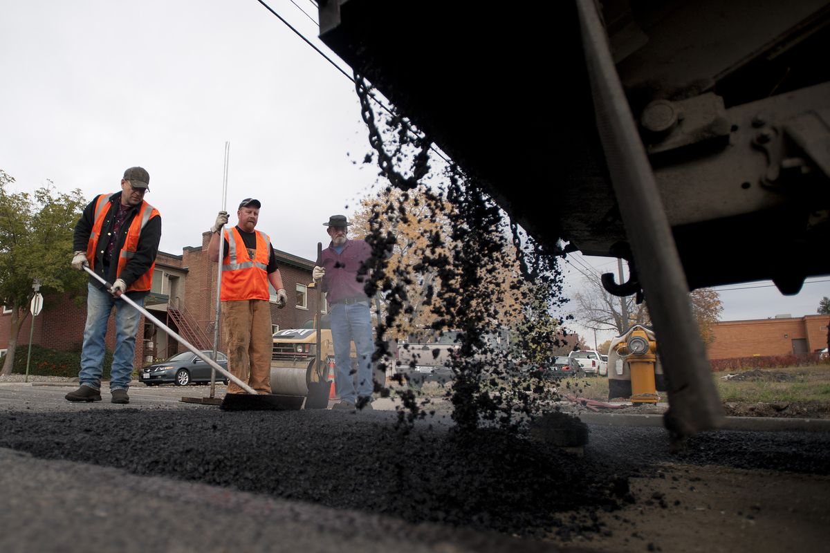 Spokane Street Department crew members, from left, Curt Borders, Sean Dennison and Rich Stapleton lay asphalt  at Cedar Street and College Avenue. With budget cuts looming, the street department might lose 14 positions.  (Colin Mulvany)