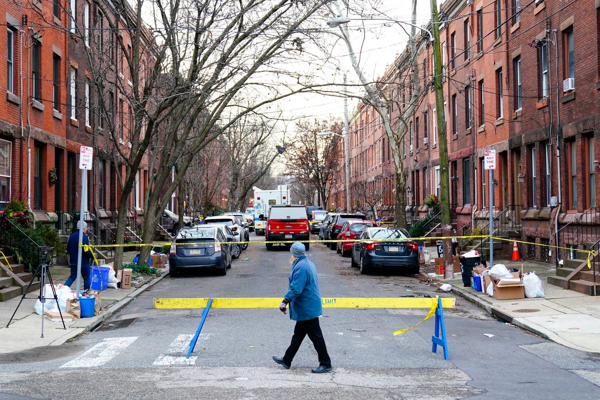 A passer-by looks over the barricade on the street of Wednesday's deadly fire in the Fairmount neighborhood of Philadelphia on Thursday, Jan. 6, 2022. Officials say it's the city's deadliest single fire in at least a century.  (Matt Rourke)