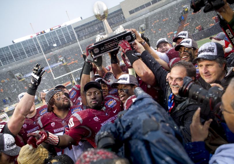 Washington State defensive members from left, Robert Barber (92, backwards hat) Kache Palacio (40) and Ivan McClennan (3) celebrate with the Sun Bowl trophy as head coach Mike Leach, right, smiles after the defense came up huge in a win over Miami during the 2015 Hyundai Sun Bowl on Saturday, Dec 26, 2015, at Sun Bowl Stadium in El Paso, TX. (Tyler Tjomsland / The Spokesman-Review)
