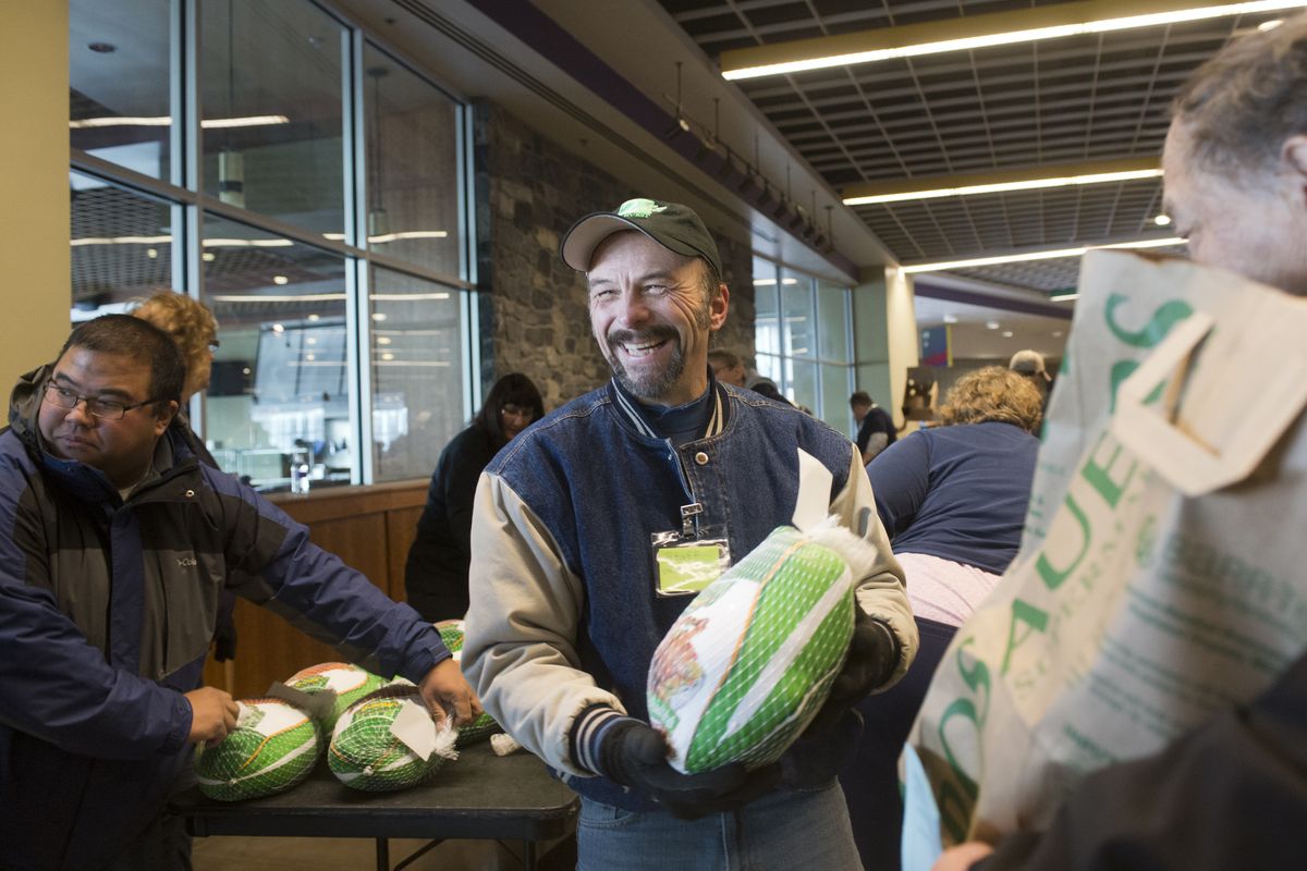 Steve Charvat jokes with clients and other volunteers while handing out turkey dinners Tuesday at the Spokane Arena. Thousands of complete meals were given out in coordination with Tom’s Turkey Drive, the Salvation Army, Second Harvest and others. (Jesse Tinsley)