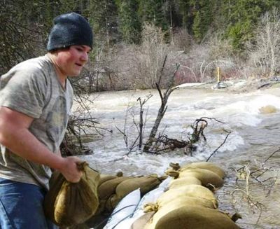 Brenden Byrne adds a sandbag to a berm next to his home on Search Light Lane off Wolf Lodge Creek Road Thursday. (Brian Walker/Coeur d'Alene Press photo)