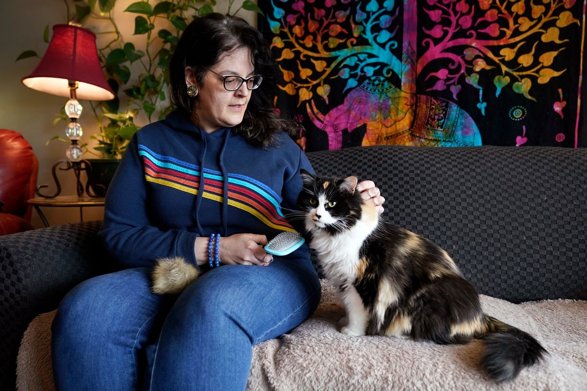 Tara Kramer sits in her apartment with her cat Busy, Friday, April 8, 2022, in Des Moines, Iowa. Month by month, more of the roughly 40 million Americans who get help buying food through the federal SNAP program are seeing their benefits plunge even as the nation struggles with the biggest increase in food costs in decades. (Charlie Neibergall)