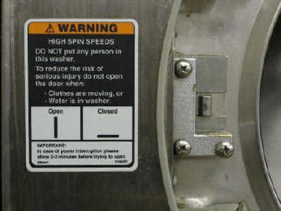 
A warning label is shown on a washing machine that is included in the book, 