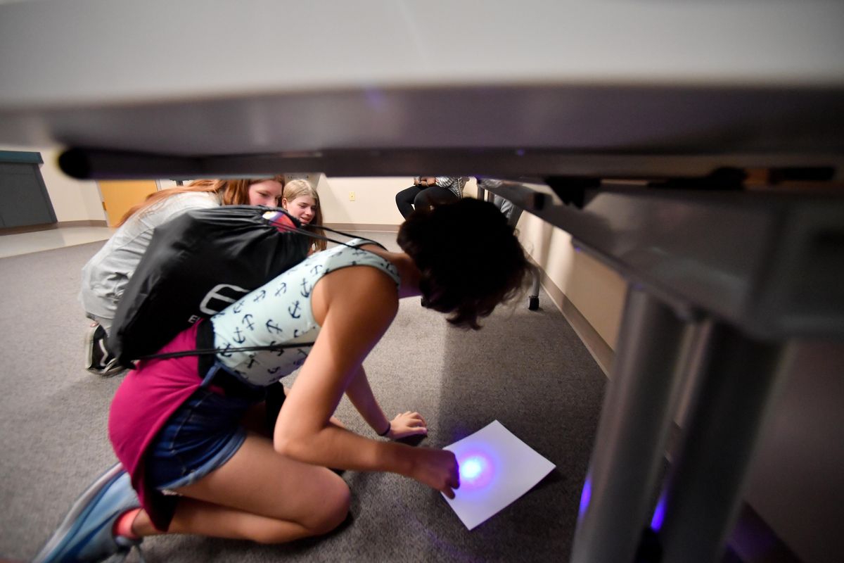 Meredith Hughes, 13, uses ultra violet light to search for clues as she works her way through an escape room on Tuesday, June 25, 2019, at Hillyard Library in Spokane, Wash. (Tyler Tjomsland / The Spokesman-Review)