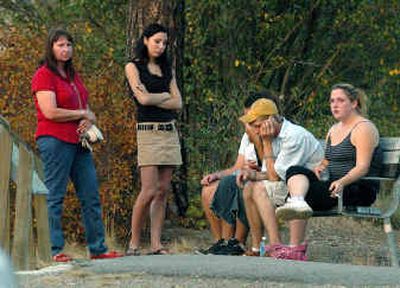 
A group of people wait in shock at Falls Park in Post Falls Tuesday evening after a friend of theirs jumped from a cliff into the Spokane River and drowned. 
 (Jesse Tinsley / The Spokesman-Review)