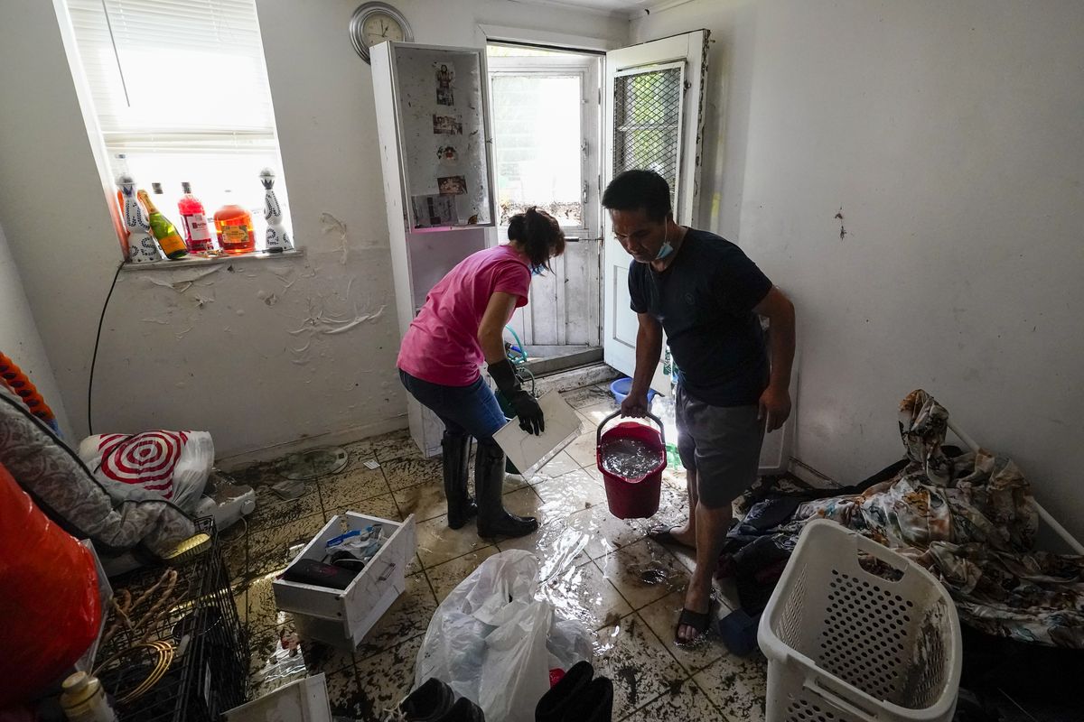 Residents of Peck Ave in the Flushing neighborhood of the Queens borough of New York use buckets to remove water from their basement apartment, Thursday, Sept. 2, 2021, in New York. The remnants of Hurricane Ida dumped historic rain over New York City, with several deaths linked to flooding in the region as basement apartments suddenly filled with water and freeways and boulevards turned into rivers, submerging cars.  (Mary Altaffer)