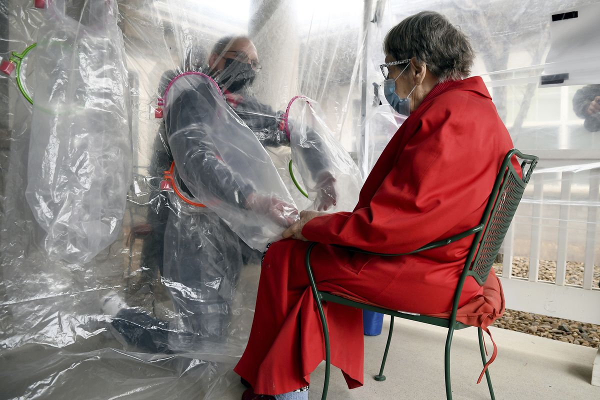 Gregg MacDonald holds hands with his mother, Chloe MacDonald, 84, at a “hug tent” set up outside the Juniper Village in Louisville, Colo., Feb. 3.  (Thomas Peipert/Assocated Press)