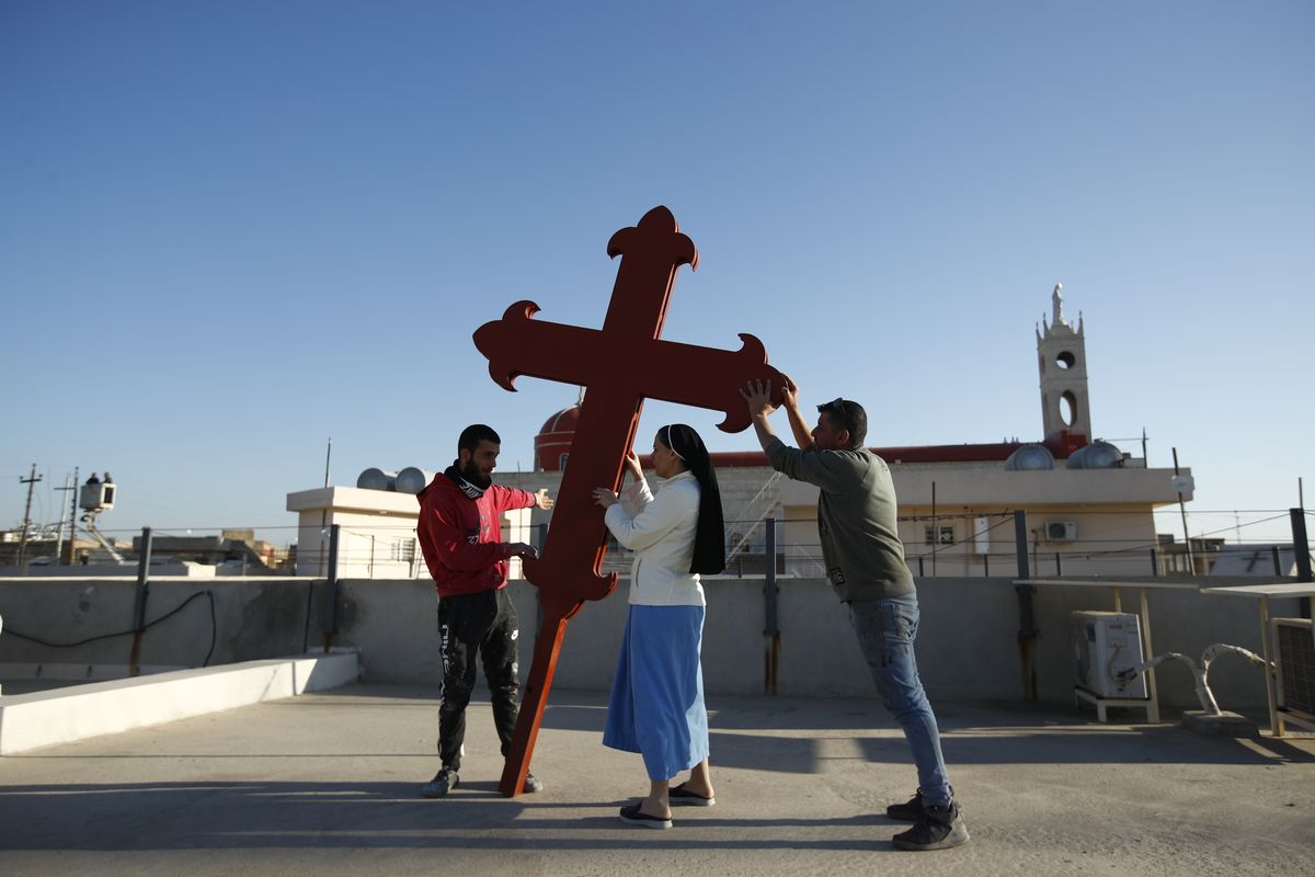 Iraqi Christians place a cross on a church in Qaraqosh, Iraq, Monday, Feb. 22, 2021. Iraq