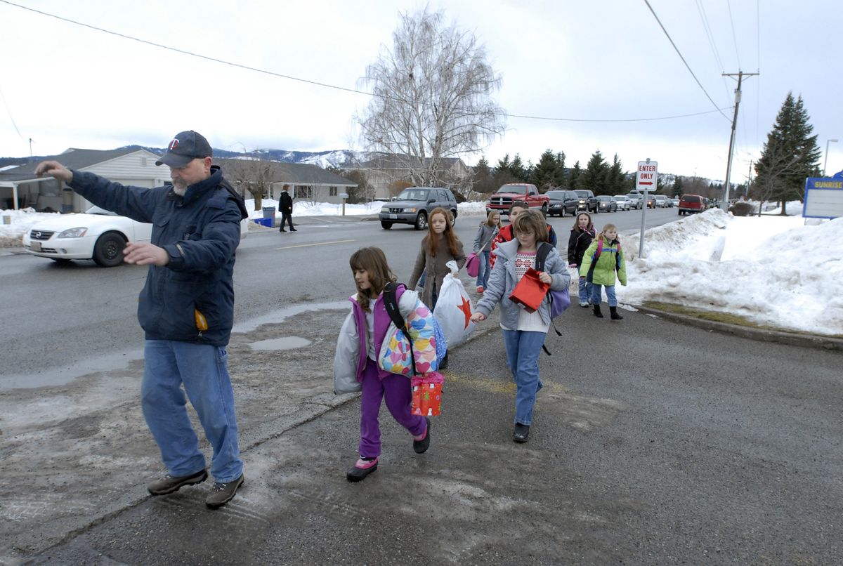 Sunrise Elementary School custodian Dave Neilsen balances himself as he leads a group of children over the icy entryway to the school as students returned from their extended winter break Thursday. Dozens of supervisors helped students get off buses and out of cars, and guided them safely into the school. Central Valley spokeswoman Melanie Rose noted that, “almost all the walkers are being driven,” which created quite a traffic jam at 24th and Adams. (J. Rayniak / The Spokesman-Review)