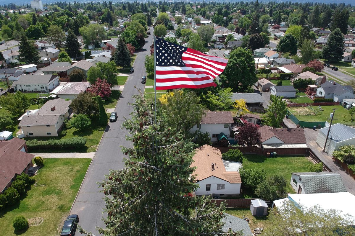 A large flag is tied to a pole on the top of a 100-foot tree in North Spokane, Thursday, May 23, 2019. Resident Alicene Robertson thought it would be a cool idea after seeing a news story where someone mounted a flag on a large tree on Fourth of July Pass in Idaho. A handyman hired by her boyfriend made the climb. (Jesse Tinsley / The Spokesman-Review)