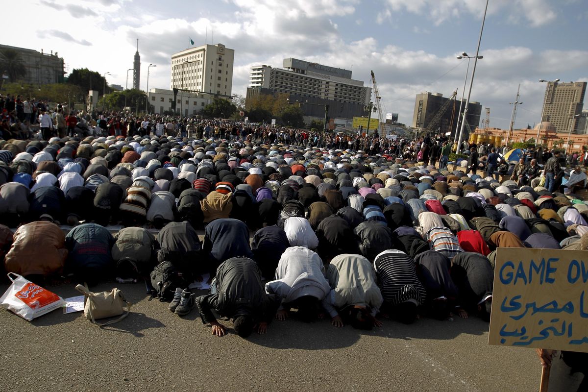 Anti-government protesters pray in Tahrir Square in Cairo, Egypt, on Monday. A coalition of opposition groups called for a million people to take to Cairo’s streets today to demand the removal of President Hosni Mubarak. The Arabic on the sign reads “I’m Egyptian, anti-destruction.”  (Associated Press)