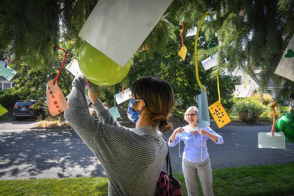 Loisa Lagger, 19, left, hangs her message on Carol WilliamÕs Gratitude Tree, Tuesday, Sept. 22, 2020, in Spokane.  (DAN PELLE)
