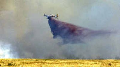 A small tanker plane from the nearby Forest Service fire center at the Coeur d'Alene Airport dumps a load of retardant on the fire at a farm near the corner of Lancaster and Highway 41 near Rathdrum on Wednesday afternoon.
(The Spokesman-Review)