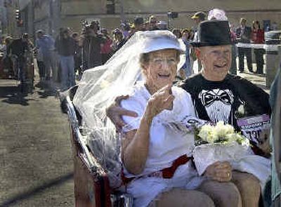 
Elisabeth Johnson-Lewis, 75, waves goodbye to her wedding party in the tight grasp of her new husband, Hugh Lewis, 78, after the duo exchanged vows Sunday morning in front of the KHQ studios before heading to the Bloomsday starting line. 
 (Amanda Smith / The Spokesman-Review)
