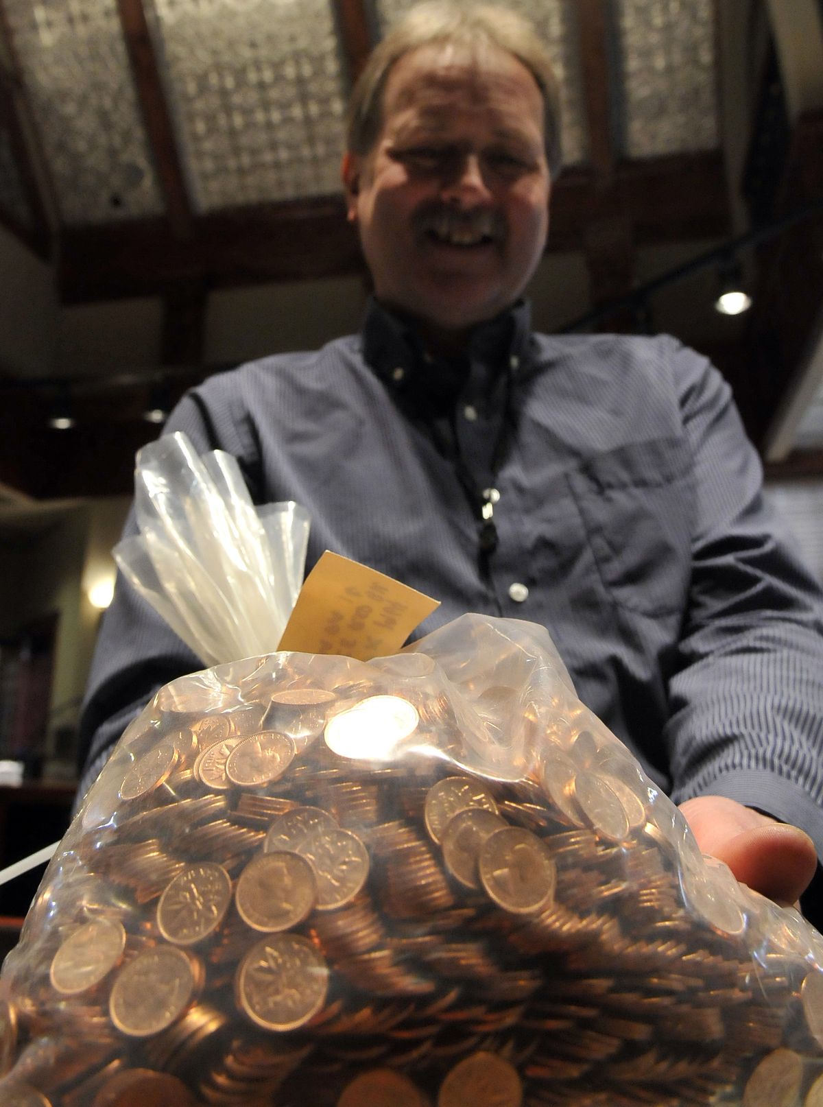 Court Peterson, who sells precious metals and coins, holds a bag of 1964 Canadian pennies at Coins Plus in Spokane on Friday. The coin will soon go out of production. (PHotos by Jesse Tinsley)
