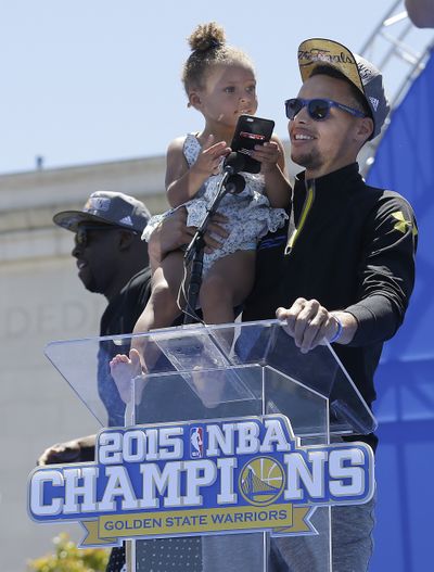 Stephen Curry, right, and daughter Riley take in rally. (Associated Press)