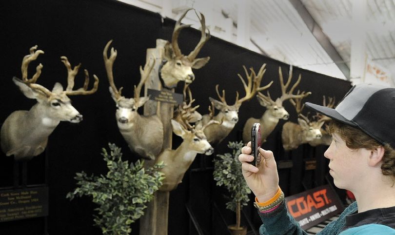 Hunter Hedquist (cq)of Spokane uses his phone to make a picture of mounted animal heads complete with horns hanging at the Big Horn Show at the Spokane County Fair and Expo site Thursday March 17, 2011. The Outdoor enthusiast show runs through the weekend.  (Christopher Anderson)
