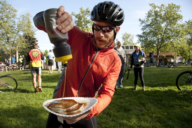 Sweet treat: Kevin Goltz, of Liberty Lake, adds maple syrup from a water bottle to his pancakes as some 150 cycling enthusiasts participated Monday in the Bike to Work Week Kickoff Breakfast in Spokane’s Riverfront Park. The weeklong event includes five neighborhood Commute of the Century rides, including today’s 5.3-mile ride starting at noon from Comstock Park, Wednesday’s ride of silence to honor cyclists killed or injured, and a wrap-up party Friday. At left is a team of Zak Designs employees heading to their Airway Heights worksite. (Dan Pelle)