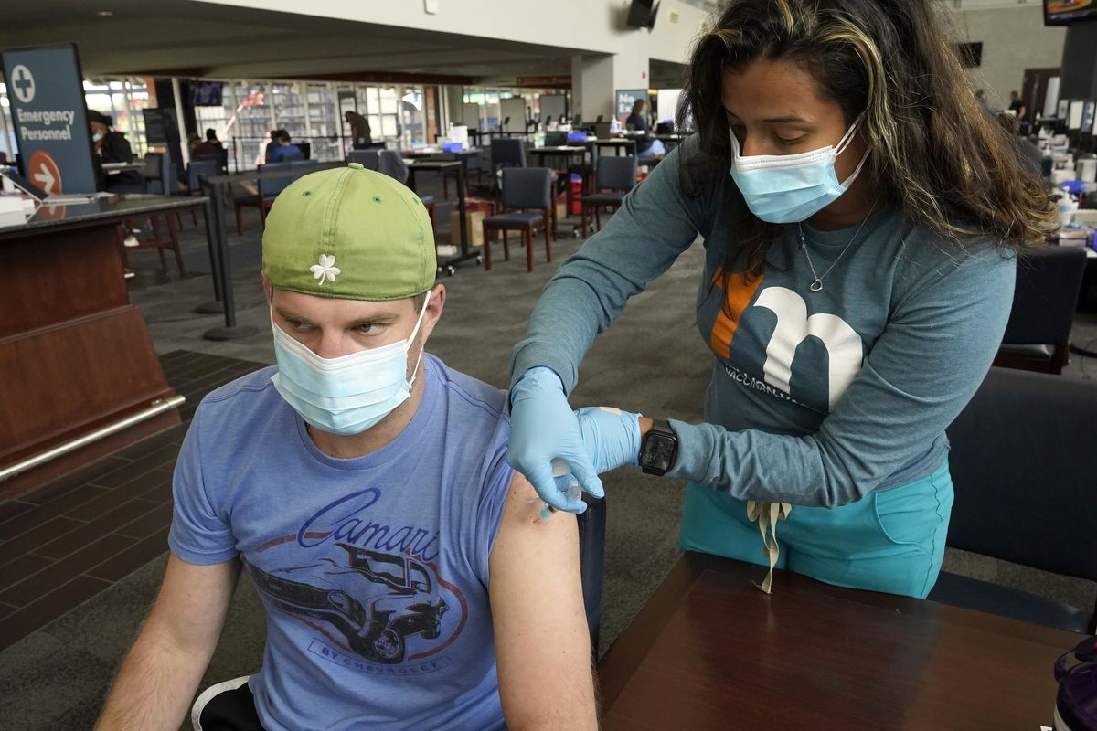 Kevin Fisher, of Quincy, Mass., left, receives his second shot of Moderna COVID-19 vaccine from RN Katherine Francisco, of Avon, Mass., right, at a mass vaccination clinic, Wednesday, May 19, 2021, at Gillette Stadium, in Foxborough, Mass. A month after every adult in the U.S. became eligible for the vaccine, a distinct geographic pattern has emerged: The highest vaccination rates are concentrated in the Northeast, while the lowest ones are mostly in the South. (Steven Senne)