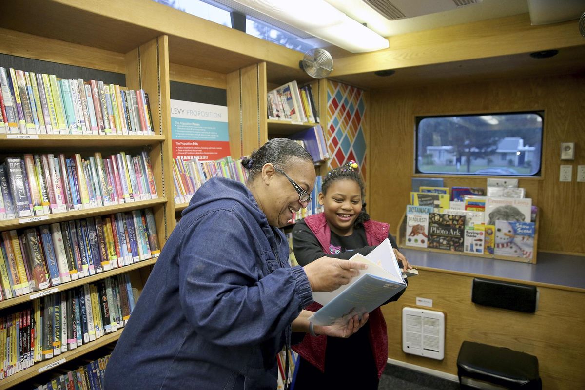 In this Thursday, Nov. 9, 2017. photo, Renee Thomas and her granddaughter Da-Mira, 9, look at library books from the bookmobile outside their new apartment in Bremerton, Wash. The pair were homeless and living in Renee