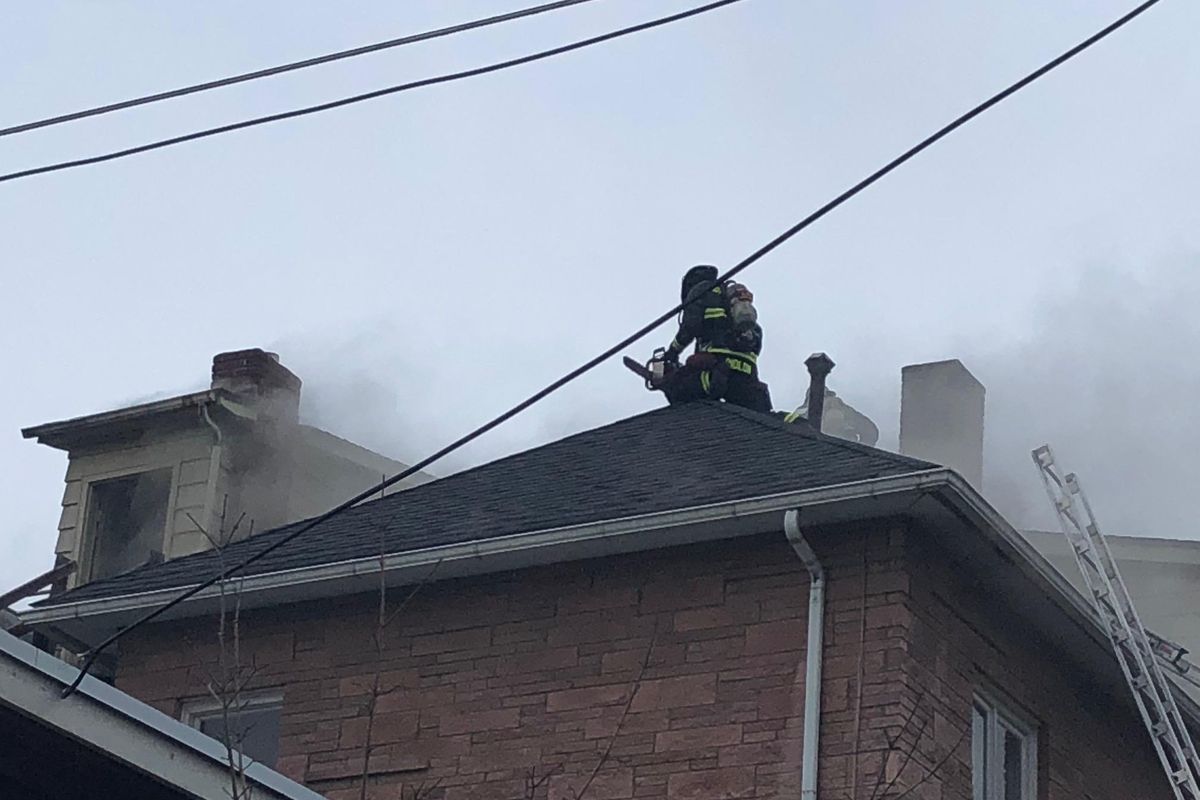 Spokane fire crews use a chainsaw to cut ventilation holes in the roof of a 9-unit apartment building at 1730 W. Pacific Ave. The fire, which was reported just after 1 p.m. Friday, was quickly knocked down with no injuries reported. (THOMAS CLOUSE / SR)