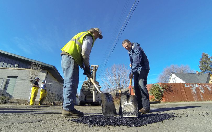 Spokane Mayor David Condon, right, and street maintenance worker Dan LaPorte fill a pothole on North Belt Street after a Monday news conference about street maintenance. City workers patch potholes with a cold-weather mixture when weather permits and switch to hot asphalt when road-building season starts in the spring. (Jesse Tinsley)