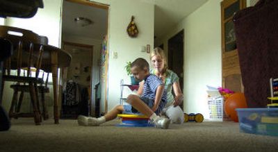 
Lila Zander works with Kade Yerxa on a spinning platform at his home during a physical therapy session recently. Zander works with the Elks program that provides the service, but it is in danger of being cut. 
 (Christopher Anderson/ / The Spokesman-Review)