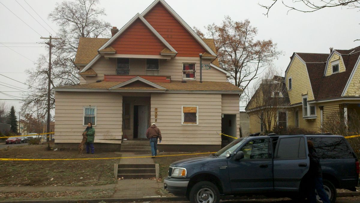 Investigators with the Spokane Police Department on scene of a homicide at 1328 W. Dean today. A resident is tending to a pitbull in front of the home. (Meghann Cuniff / The Spokesman-Review)
