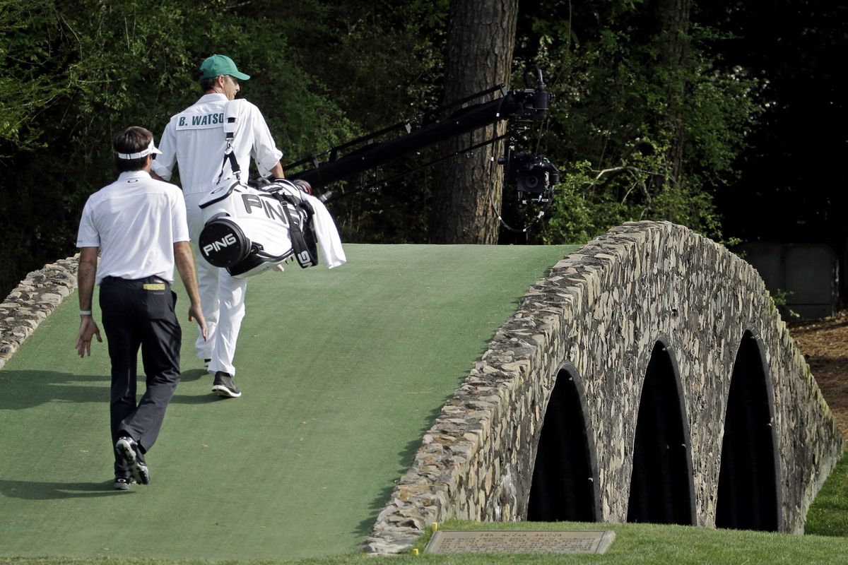 Bubba Watson walks across the Hogan Bridge with his caddie, Ted Scott, during Sunday’s final round at Augusta. (Associated Press)