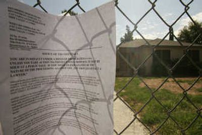 
A notice is posted on the front gate of a home disclosing that the owner of the property is at 