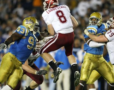 UCLA’s Kevin Kooyman, left, closes in for a first-half sack on airborne Washington State quarterback Marshall Lobbestael.  (Associated Press / The Spokesman-Review)